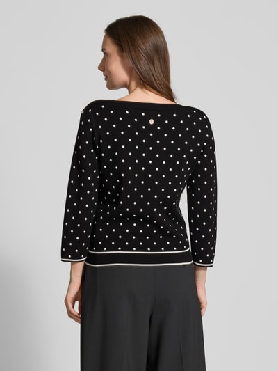 Frauenmodel trägt Strickpullover aus Viskose-Mix Modell 'Konstantina' von JOOP! mit weißen Punkten, Schwarz, tailliert, Ganzkörperansicht Rückansicht.