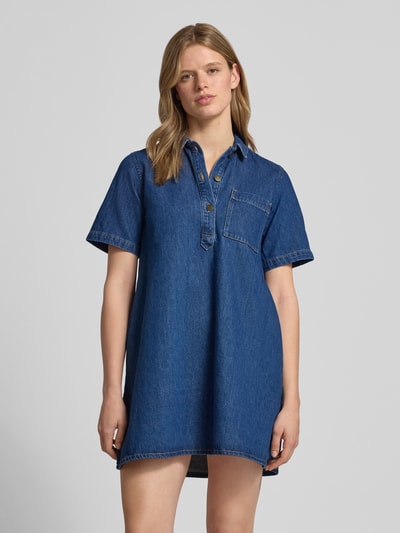 Frauenmodel trägt Relaxed Fit Minikleid in Denim-Optik Modell 'Amara' von JJXX aus reiner Baumwolle, Umlegekragen, kurzärmelig, Ganzkörperansicht von vorne.