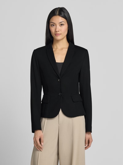 Vrouwenmodel draagt Slim Fit Blazer aus Viskose-Mix van Marc Cain, zwart, reverskraag, 2-knoopsluiting, klepzakken, mix van viscose en elastaan, ruglengte maat 36 56 cm, borstwijdte 23 cm, mouwlengte 63 cm, ganzebodyaanzicht van voren.