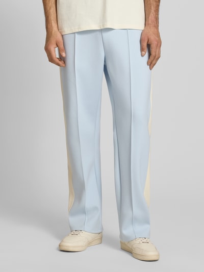 Männermodel trägt Straight Fit Sweatpants mit Logo-Stitching von KARL KANI in Hellblau, Elastischer-Material-Mix mit Baumwoll-Anteil, Ziernähte, Ganzkörperansicht von vorne.