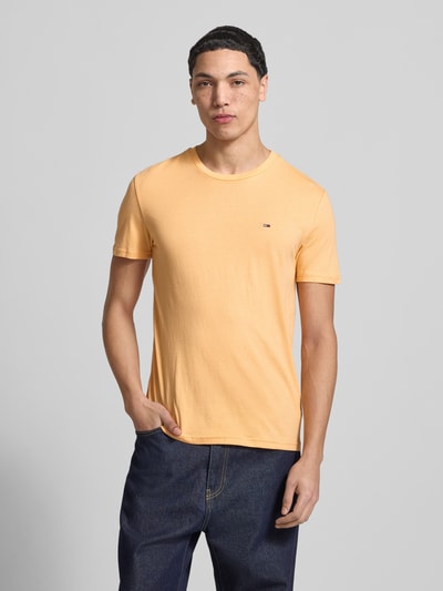 Mannenmodel draagt Slim fit T-shirt uit katoenmix Model 'JASPE HERITAGE' van Tommy Jeans met gemêleerde look, logostitching, korte mouw, voorkant volledige lichaamsopname.
