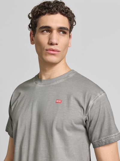 Männermodel trägt Regular Fit T-Shirt aus reiner Baumwolle von Diesel in Grau mit Label-Details und Used-Look, Nahaufnahme Oberkörper. Herren T-Shirt mit Rundhalsausschnitt, Rückenlänge bei Größe M 70 cm.