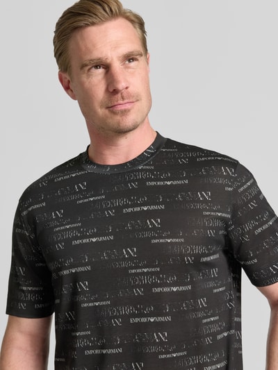 Männermodel trägt T-Shirt mit Logo-Muster und Rundhalsausschnitt von Emporio Armani, Lyocell-Baumwoll-Mix, Regular-Fit, Nahaufnahme Oberkörper.
