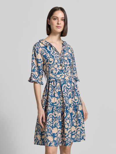 Frauenmodel trägt Knielanges Kleid aus Viskose im Allover-Look von Christian Berg Woman in A-Linie mit V-Ausschnitt, Volants und Bindegürtel, Ganzkörperansicht von vorne.