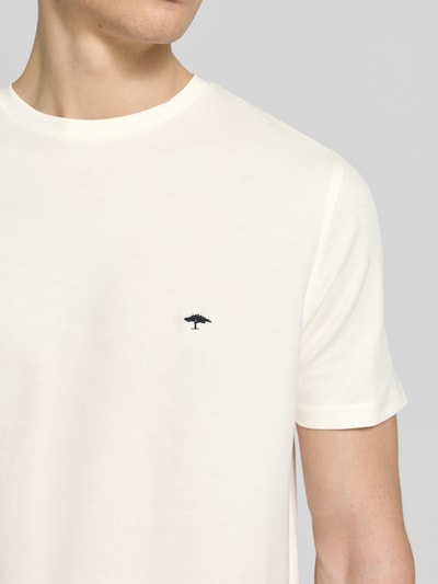 Männermodel trägt Herren T-Shirt Regular Fit T-Shirt mit Logo-Stitching von Fynch-Hatton in Creme, Reine Baumwolle, Nahaufnahme Oberkörper. Rückenlänge bei Größe M: 68 cm, Rundhalsausschnitt.