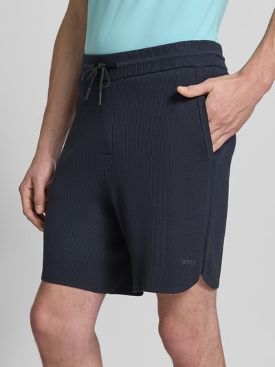 Mężczyzna nosi Regular Fit Stoffshorts aus Viskose-Mix model 'KN_UNION SH' od BOSS Green, ciemny kolor, ziarnista faktura, zbliżenie górnej części nogawek, zdjęcie z przodu.