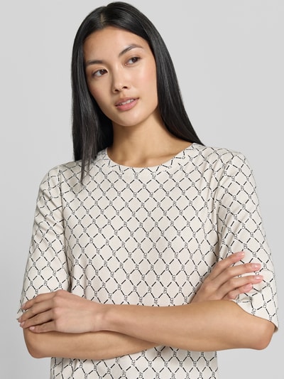 Modelka damska ma na sobie Regular Fit T-Shirt mit Allover-Logo-Print od Marc Cain z mieszanki bawełny, nadruk z logo na całej powierzchni, okrągły dekolt, rękaw o dł. 1/2, Długość tyłu w rozmiarze 36: 58 cm, zbliżenie na górną część ciała.