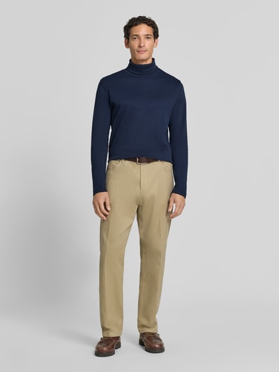 Männermodel trägt Regular Fit Longsleeve aus reiner Baumwolle mit Rollkragen von Christian Berg Men in Dunkelblau, Ganzkörperansicht von vorne. Rugose Oberflächenstruktur, kombiniert mit beigen Stoffhosen und dunklen Schuhen, elastische Abschlüsse, Rückenlänge bei Größe M: 70 cm.