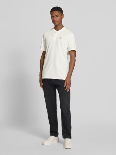 Männermodel trägt Regular Fit Poloshirt aus Baumwoll-Mix von s.Oliver RED LABEL in Weiß, unifarben mit Label Patch, Ganzkörperansicht von vorne