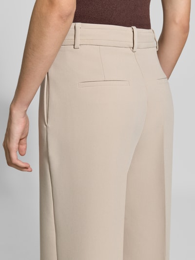 Frauenmodel trägt Straight Fit Hose mit Viskose-Anteil von MORE & MORE in Beige, feine Struktur, Bügelfalten, Ganzkörperansicht Rückansicht.