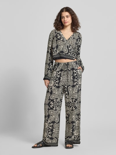 Frauenmodel trägt Shaped Fit Bluse aus reiner Viskose Modell 'LEMZA' von Only mit Floralem-Allover-Muster, Wickeloptik, Bindegürtel, V-Ausschnitt, Langarm und feiner Webstruktur; Ganzkörperansicht von vorne.