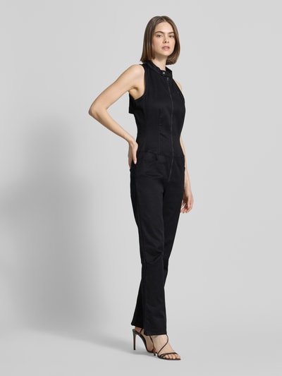 Vrouwenmodel draagt zwarte Jumpsuit met Reißverschluss Modell 'Lynn' van G-Star Raw, mix van katoen en elastaan, regular fit, opstaande kraag, ruglengte maat S 45 cm, borstwijdte 29 cm, totale lengte 148 cm, binnenbeenlengte 76 cm, geheel zwarte kleur, materiaal met gladde textuur, geheel lichaam van voren