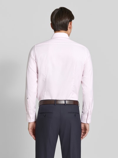 Męski model nosi Slim Fit Businesshemd aus reiner Baumwolle Modell 'Spread Kent' od Seidensticker w delikatnym różowym kolorze z subtelnym prążkowaniem, ciemne spodnie, tekstura gładka, kontekst: Herren Businesshemd von Seidensticker, ujęcie całej sylwetki z tyłu.