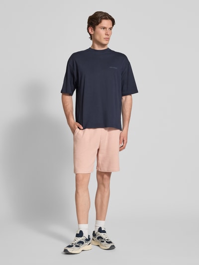 Männermodel trägt Shorts aus Baumwoll-Mix mit Strukturmuster Modell 'KNOX' von Redefined Rebel in Rosa, Relaxed-Fit, elastischer Bund mit Tunnelzug, Ganzkörperansicht von vorne.