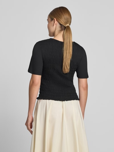 Frauenmodel trägt T-Shirt aus Viskose-Elasthan-Mix mit Smok-Details von Comma, Schwarz, Slim-Fit, Rückenlänge 47 cm, Ganzkörperansicht Rückansicht.
