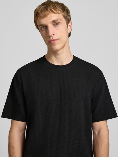 Männermodel trägt Regular Fit T-Shirt aus Baumwoll-Mix Modell 'KIAN' von Only & Sons, Optik: Unifarben, Piqué-Struktur, Nahaufnahme Oberkörper.