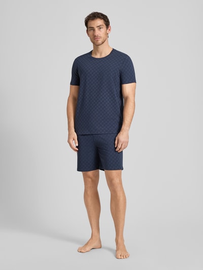 Männermodel trägt Shorts aus Baumwolle mit Logo-Muster von JOOP! Collection in Dunkelblau, Regular-Fit, Ganzkörperansicht von vorne.