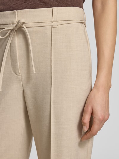 Frauenmodel trägt Wide Leg Stoffhose mit Viskose-Anteil von s.Oliver BLACK LABEL in Melange-Optik, fixierte Bügelfalten, Bindegürtel, seitliche Eingrifftaschen, Nahaufnahme Oberkörper.