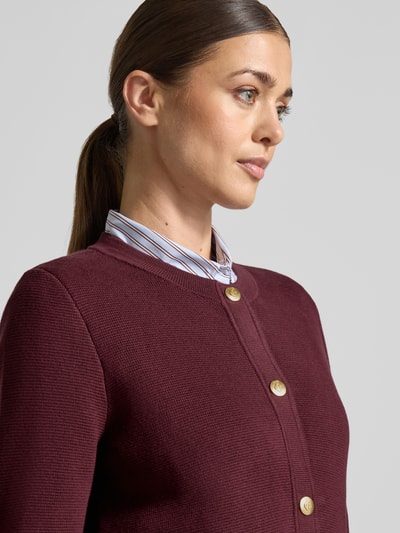 Frauenmodel trägt Regular Fit Strickjacke aus reiner Baumwolle von GANT in Dunkelrot, feine Struktur, Hemdkragen sichtbar, Nahaufnahme Oberkörper, Damen Strickjacke.