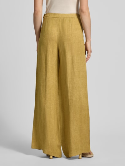 Männermodel trägt szerokie, musztardowe spodnie z lnu Wide Fit Leinenhose mit Eingrifftaschen Modell 'LOTTELIA' von Marella, długość wewnętrzna nogawki 89 cm, szerokość w rozmiarze 36: 37 cm, model z wpuszczanymi kieszeniami i zamkiem błyskawicznym, widok całej sylwetki z tyłu.