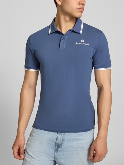 Männermodel trägt Slim Fit Poloshirt mit Logo-Stitching Modell 'Reed' von SERGIO TACCHINI, blau, Baumwoll-Mix, Ganzkörperansicht von vorne.