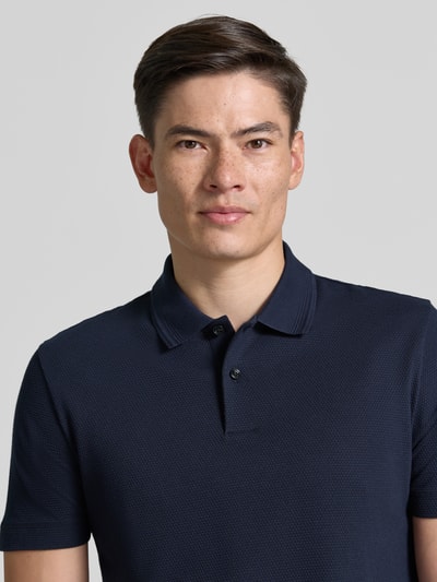 Mężczyzna nosi Regular Fit Poloshirt aus Baumwoll-Mix Modell 'PARLAY 240' od BOSS, granatowy, gładki, krótki rękaw, krój regular fit, dekolt w szpic, kołnierzyk polo, naszywka z logo, bawełniana mieszanka, zapięcie na dwa guziki, tekstura subtelna, zbliżenie na górną część tułowia