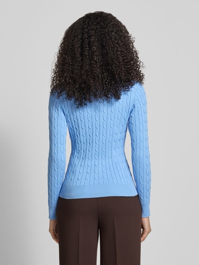 Vrouwenmodel draagt gebreide pullover met kabelpatroon en labelstitching van Gant, katoenmix met stretch, slim fit, ruglengte maat S 58 cm, mouwlengte 61 cm, dames, blauwe tinten, kabelstructuur, volledig lichaamsaanzicht rugaanzicht.