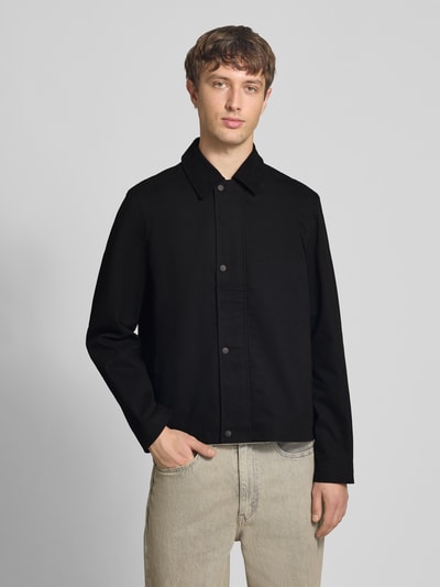 Männermodel trägt schwarze Jacke mit Umlegekragen Modell 'GRAHAM' von Jack & Jones, Regular Fit, Knopfleiste, Nahaufnahme Oberkörper.