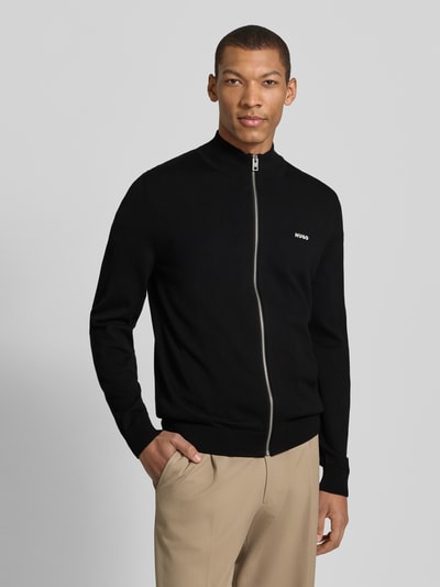 Männermodel trägt Regular Fit Gebreid jack uit puur katoen model 'SAN JACOMO' van HUGO, look: effen, met ritssluiting, schipperskraag, labelstitching, lange mouw, rompzoom en mouwboord geribd, materiaalverwerking: knitwear, kleur zwart, voorkant, bovenlichaam.