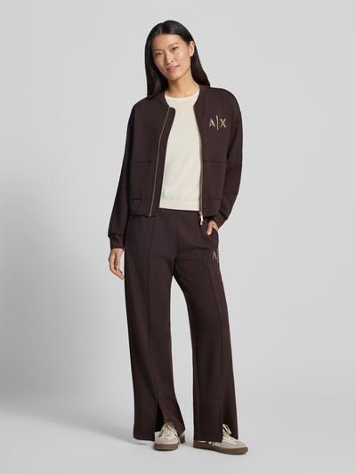 Vrouwenmodel draagt Straight Fit Sweatpants uit elastische viscosemix van Armani Exchange, donkerbruin met labeldetail en pijpsplitten, elastische band, binnenbeenlengte bij maat S 77 cm, full body vooraanzicht.