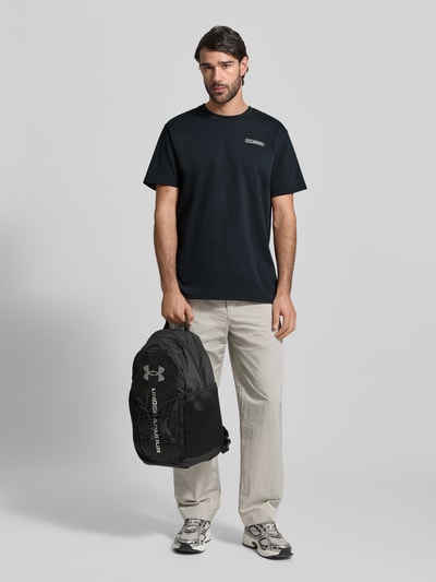 Männermodel trägt Regular Fit T-Shirt mit Logo-Applikation von Under Armour, Baumwoll-Mix, Rundhalsausschnitt, schwarze Farbe, Ganzkörperansicht von vorne.