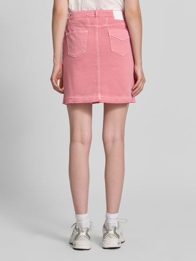 Vrouwenmodel draagt Straight Fit Minirok in denimlook van Marc Cain uit elastische katoenmix met gulp, achterzakken, knoop- en ritssluiting, bandwijdte maat 36: 37 cm, totale lengte maat 36: 44 cm, roze kleur, gladde textuur, achteraanzicht full body
