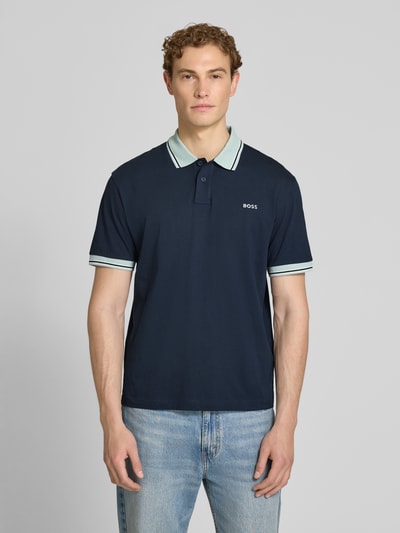Männermodel trägt Regular Fit Poloshirt aus reiner Baumwolle Modell 'BLOCKS' von BOSS Orange, navy, kurzarm, Piqué, Ganzkörperansicht von vorne.