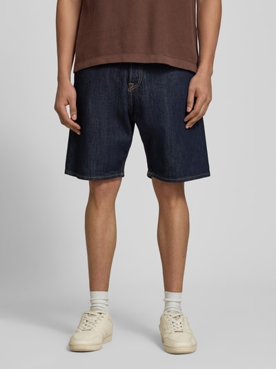 Männermodel trägt Relaxed Fit Jeansshorts Modell 'TONY' von Jack & Jones aus dunkelblauem Baumwoll-Elasthan-Mix mit Eingrifftaschen, Ganzkörperansicht von vorne. Bundweite bei Größe M: 42 cm, Innenbeinlänge: 21 cm.