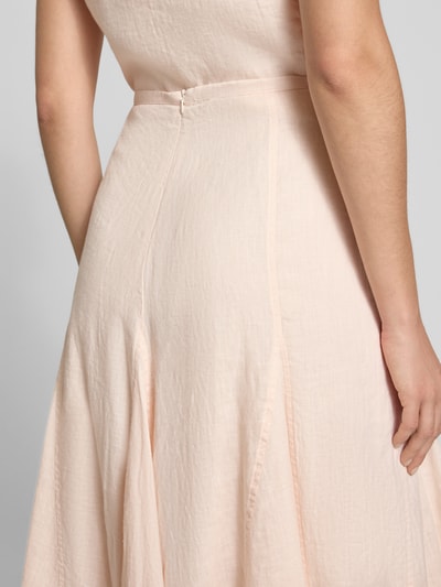 Frauenmodel trägt Leinenrock in A-Linie mit Teilungsnähten von Emily Van den Bergh, zart rosé, feine Struktur, Nahaufnahme Rückenansicht. Damen, Reines Leinen, A-Linie, Midirock, Teilungsnähte, Bundweite bei Größe 36: 36 cm, Gesamtlänge bei Größe 36: 85 cm.