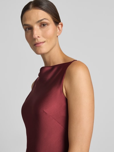 Frauenmodel trägt Figurbetontes Cocktailkleid mit Viskose-Anteil von Jake*s Cocktail in dunklem Rot, glatte Textur, Nahaufnahme Oberkörper.