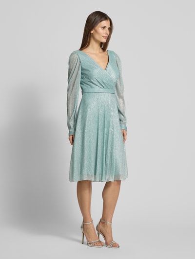 Modelka nosi Regular Fit Kleid in Wickel-Optik von TROYDEN COLLECTION z błyszczącą siateczką, dekoltem w serek, długość tyłu 90 cm, szerokość w rozmiarze 36: 37 cm, długość rękawów 67 cm, taliowany krój, wszyty zamek błyskawiczny, mintowa barwa; widok całej sylwetki z przodu.