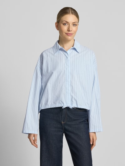 Vrouwenmodel draagt Boxy Fit Blouse met verdekte knoopsluiting Model 'FIONEL' van DRYKORN, puur katoen, overhemdkraag, tunnelkoord, ruglengte maat 36: 54 cm, mouwlengte maat 36: 50 cm, lichtblauw met fijne strepen, boxy fit, gladde textuur, Ganzkörperansicht van voren.