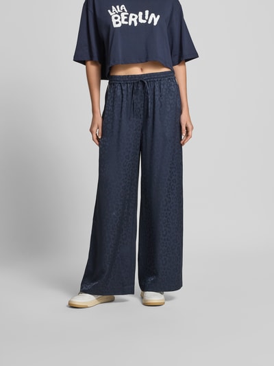 Frauenmodel trägt Wide Fit Sweatpants mit Viskose-Anteil von Lala Berlin, dunkelblau mit Allover-Animal-Print, Ganzkörperansicht von vorne.