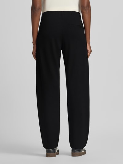 Frauenmodel trägt schwarze Weite Hose aus Viskose-Mix von ARMEDANGELS, lockere Form, glatte Textur, Ganzkörperansicht Rückansicht, Damen Weite Hose.