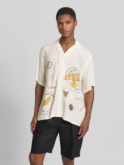 Męski model nosi koszulę casualową Relaxed Fit Freizeithemd aus reiner Viskose Modell 'HOTEL AMOUR' von SELECTED HOMME, efekt: wzór na całej powierzchni, kołnierzyk koszulowy, listwa guzikowa na całej długości, pas na plecach, rękaw: krótki, materiał: wiskoza, kremowe i żółte detale, delikatna tekstura, Ganzkörperansicht von vorne.