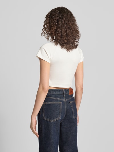 Frauenmodel trägt Cropped T-Shirt mit Logo-Print von ANOTHER COTTON LAB in Weiß, aus reiner Baumwolle, Rundhalsausschnitt, Rückenlänge 36 cm, Ganzkörperansicht Rückansicht.