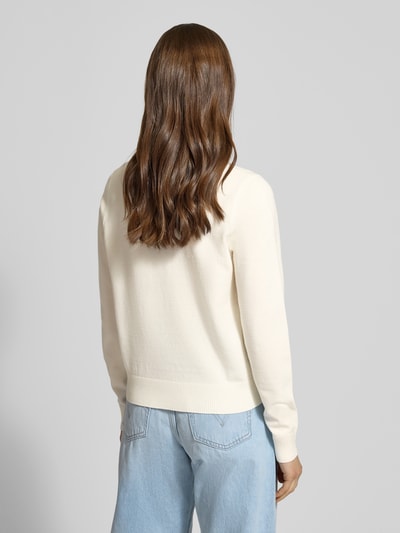 Männermodel trägt Strick-Cardigan aus Viskose-Mix mit langen Ärmeln von Review, krój regular fit, dzianina kremowa, widoczne rippbündchen na rękawach i u dołu, haftowane logo, zapięcie na guziki, długość tyłu 53 cm, długość rękawa 63 cm, kontekst damskiego swetra, ganzkörperansicht rückansicht.