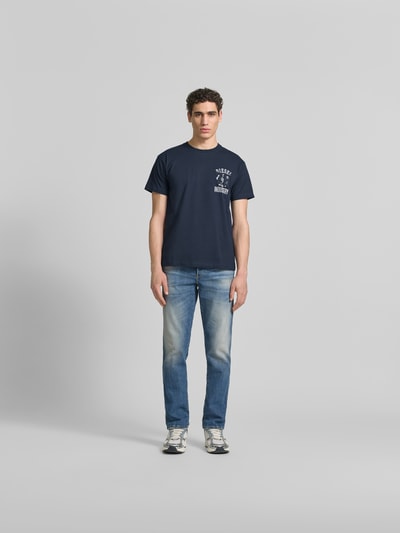 Männermodel trägt Regular Fit T-Shirt aus reiner Baumwolle von Diesel in Dunkelblau mit Label-Applikation, Ganzkörperansicht von vorne.