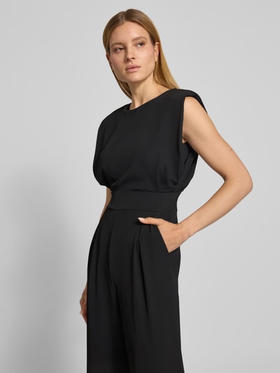 Frauenmodel trägt Regular Fit Jumpsuit mit Rundhalsausschnitt von Rinascimento in Schwarz, ärmellos, mit Kellerfalten; Nahaufnahme Oberkörper.