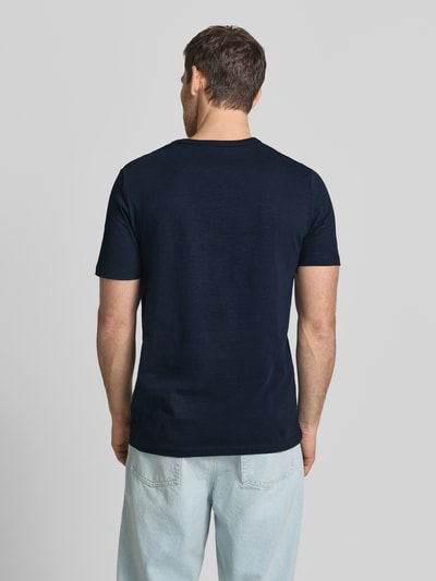 Męski model nosi Regular Fit T-Shirt aus reiner Baumwolle od s.Oliver RED LABEL, efekt: jednolity kolor, krój regular fit, nadruk z motywem, rękaw: krótki rękaw, bawełna, Ganzkörperansicht Rückansicht.