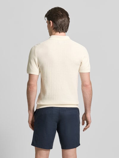 Männermodel trägt Poloshirt mit kurzem Reißverschluss und Polokragen von MCNEAL aus Bio-Baumwolle in Creme, Rückansicht, Ganzkörperansicht.