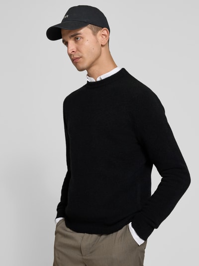 Männermodel trägt Pullover aus Woll-Mix mit Yak-Anteil von Filippa K in Schwarz, Strick-Optik, Stehkragen, Ganzkörperansicht von vorne.