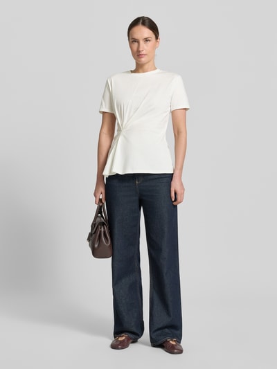 Frauenmodel trägt Damen T-Shirt Regular Fit T-Shirt mit Raffungen Modell 'KIWI' von Mango, Reine Baumwolle, Kurzärmelig, Rundhalsausschnitt, Rückenlänge bei Größe S: 61 cm, weiße Farbe, leichte Textur, dicke, gerade geschnittene Jeans, braune Schuhe, Ganzkörperansicht von vorne.