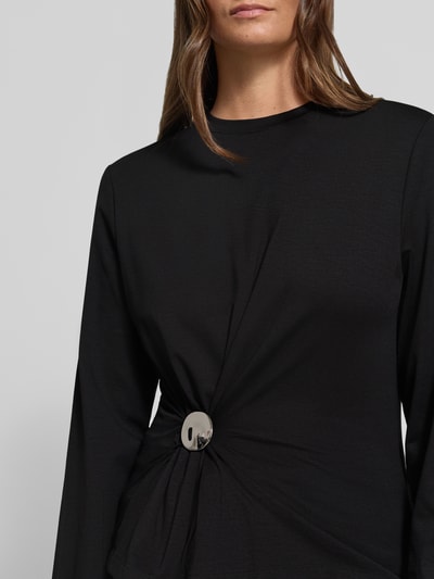 Vrouwenmodel draagt shirt met lange mouwen van stretchmateriaal, slim fit, drapering, ronde hals, model 'ALITH' van DRYKORN, detailopname bovenlichaam. Ruglengte maat S: 59 cm.